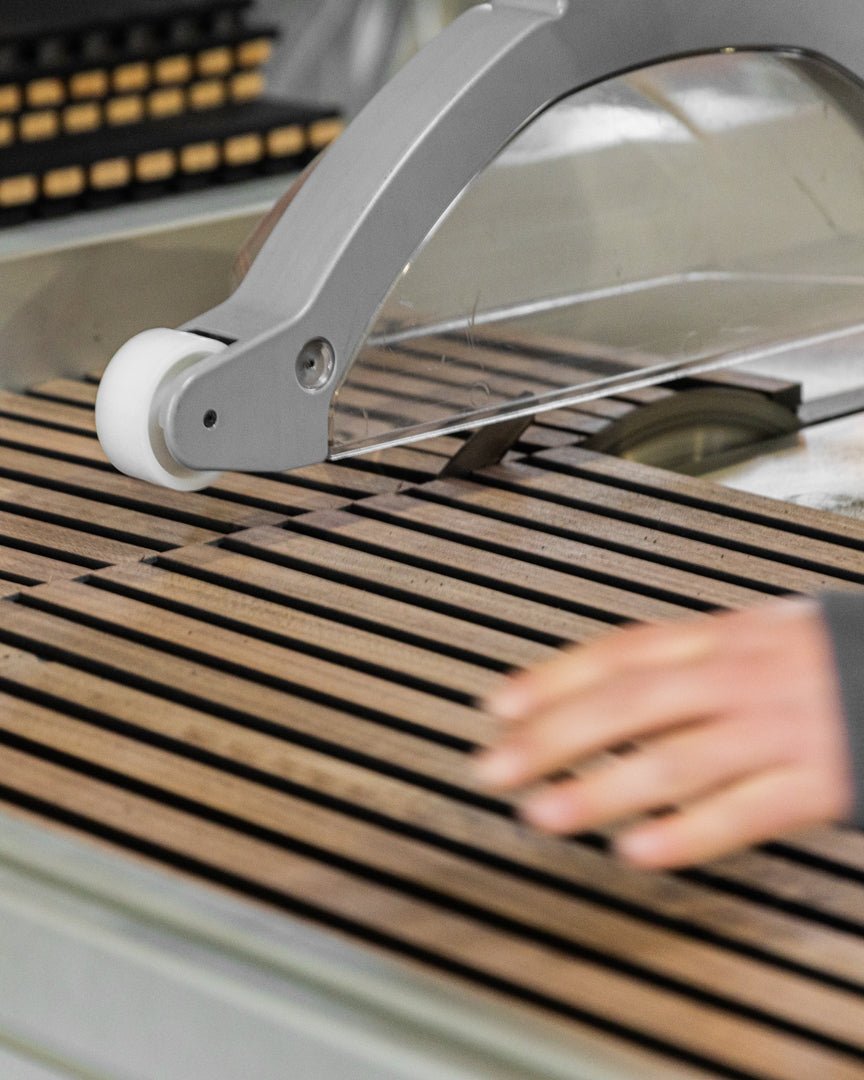 A hand uses WoodUpps precise Cutting service to trim evenly spaced acoustic panel slats, ensuring accurate alignment for Nordic wood wall installation.